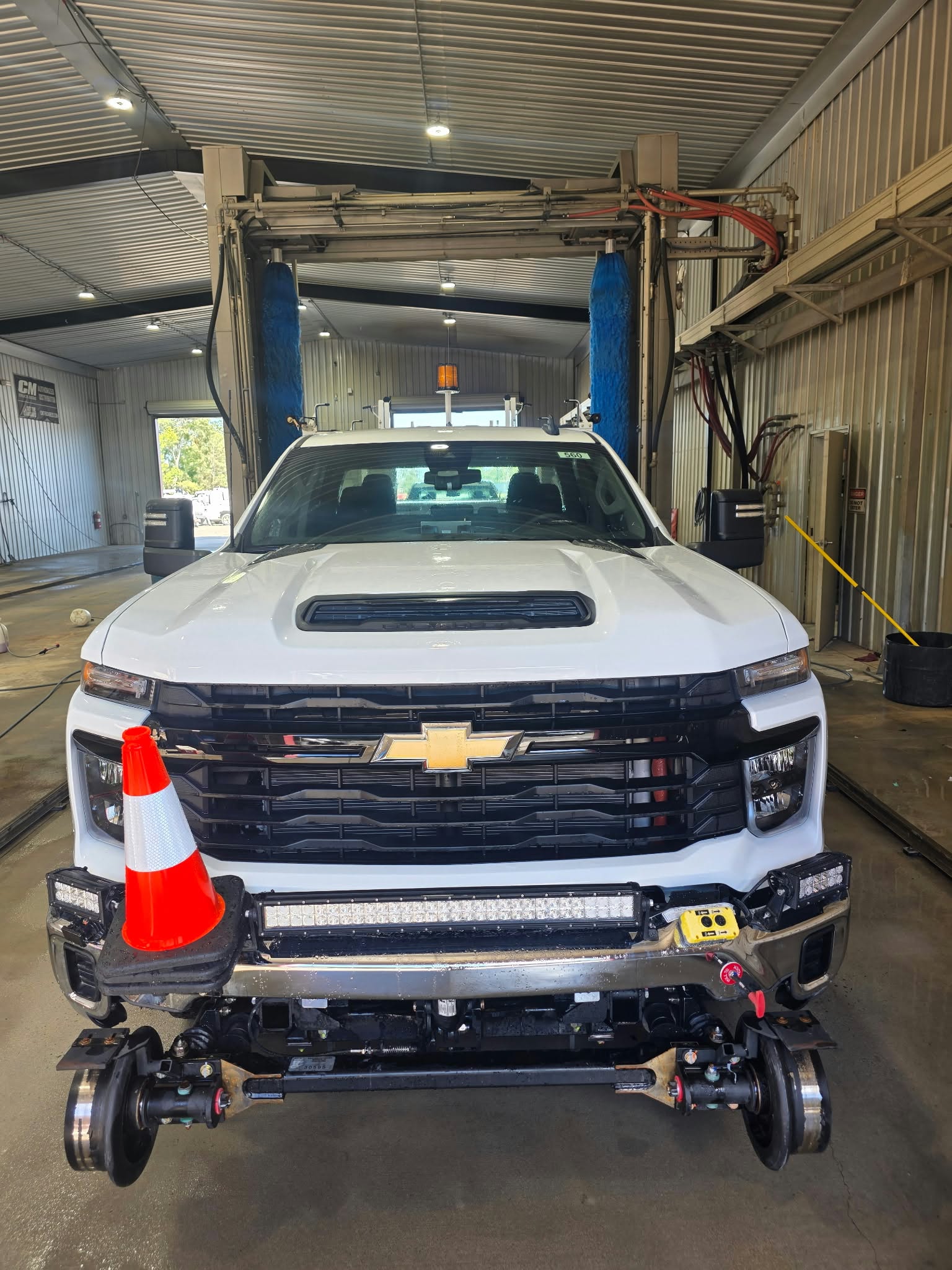 White Chevrolet work truck inside Station Truck’s wash bay with blue wash brushes