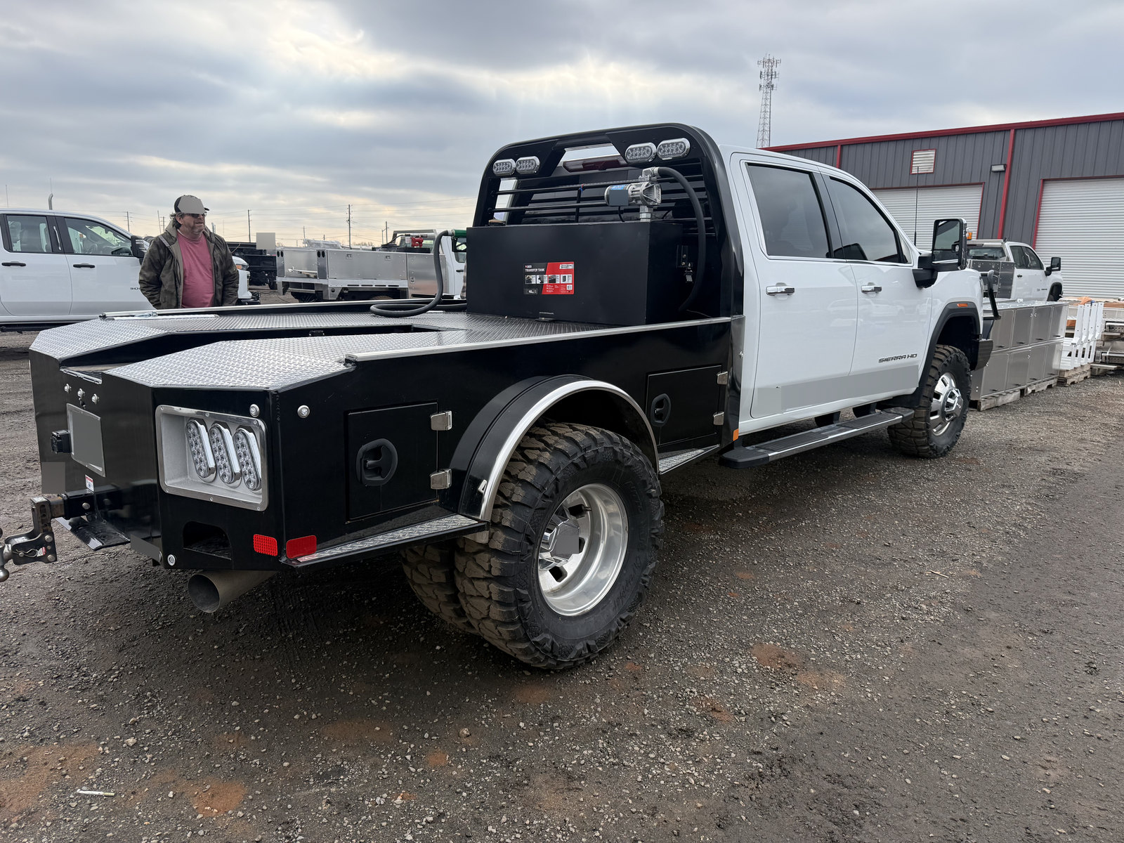 Rear three-quarter view of a white crew-cab pickup with a black utility body