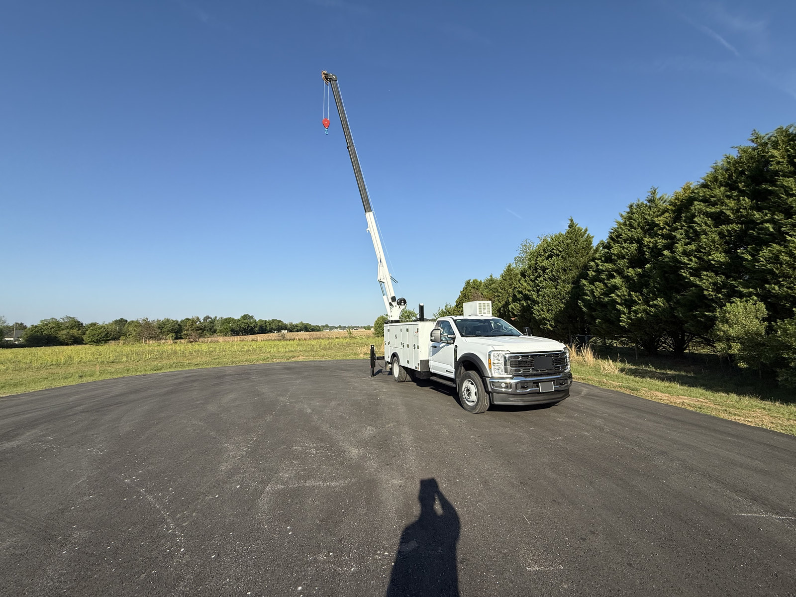 White service truck outdoors with its boom crane fully extended